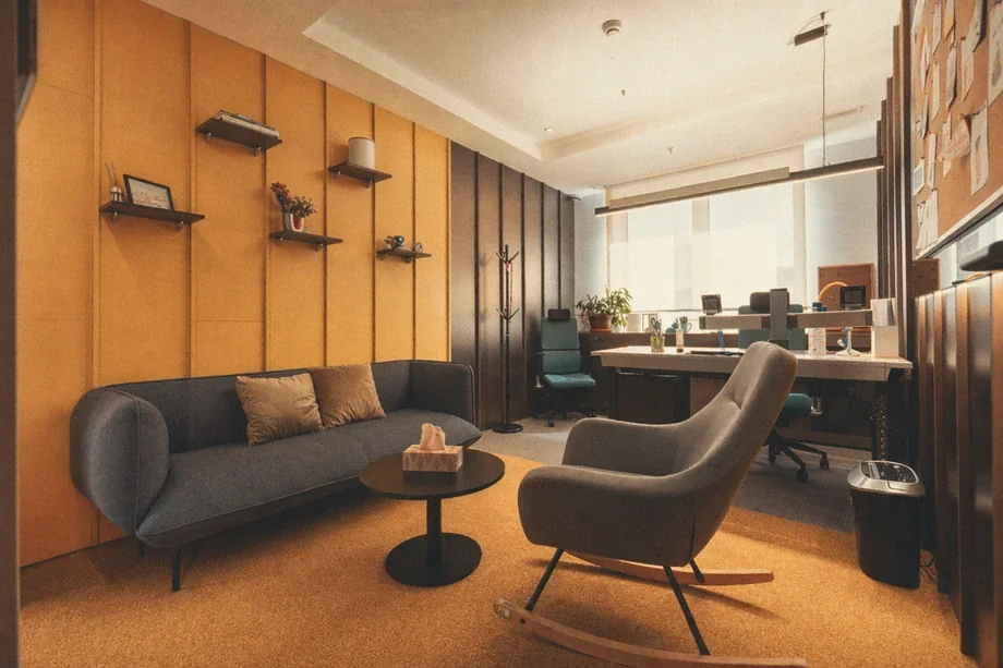 Quiet private office with grey sofa, rocking chair, and shelving at Coinis HQ