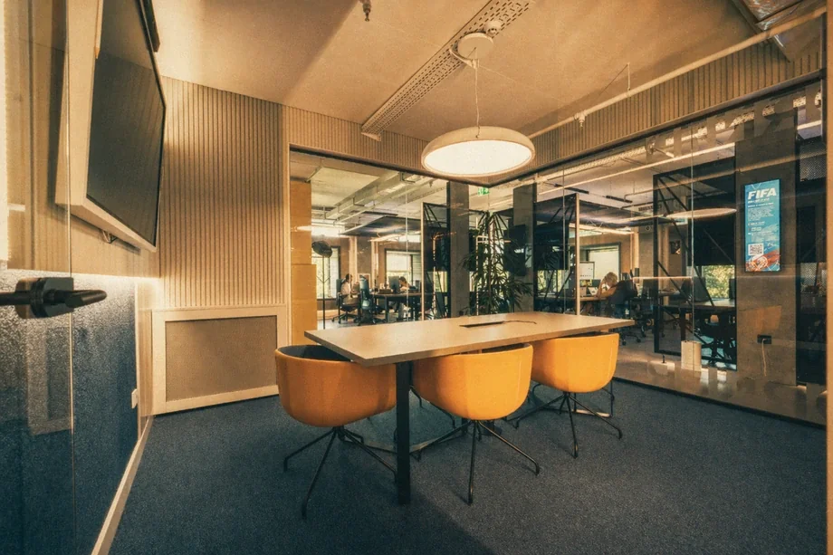 Meeting room with mustard yellow chairs and pendant light overlooking the open floor at Coinis HQ