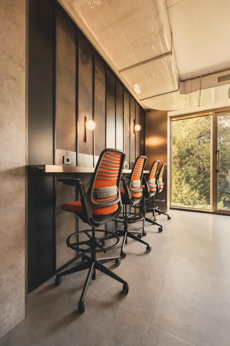 Focus counter with four orange striped barstools against a black acoustic panel wall at Coinis HQ