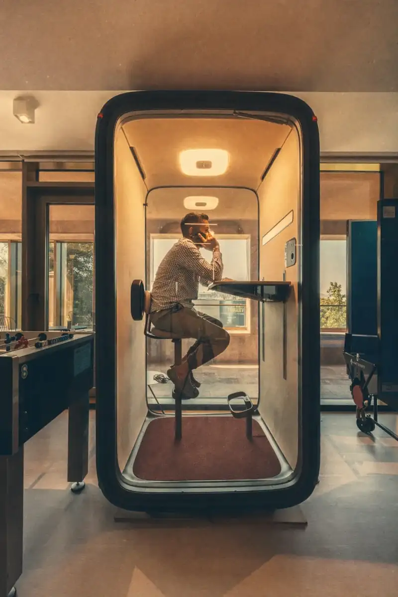 Soundproof phone booth pod in use at Coinis HQ beside a foosball table