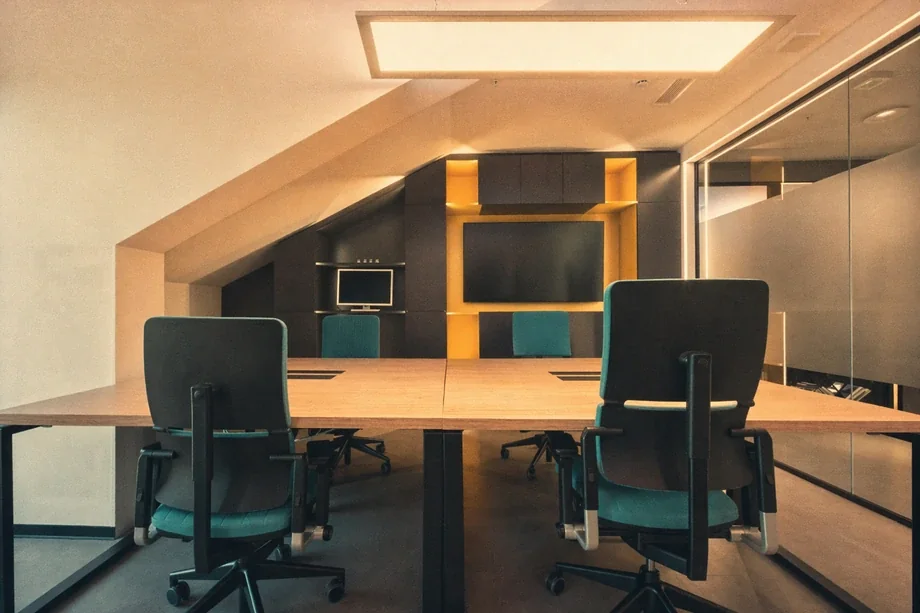 Attic meeting room with angled ceiling, teal office chairs, and yellow wall niche at Coinis HQ