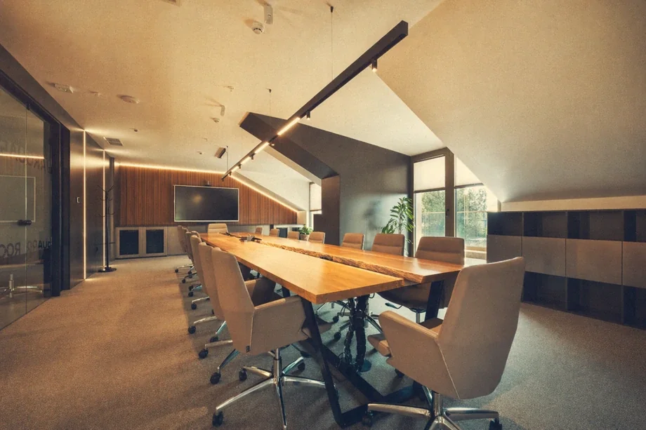 Boardroom with long live-edge wooden table, beige swivel chairs, and wall display at Coinis HQ