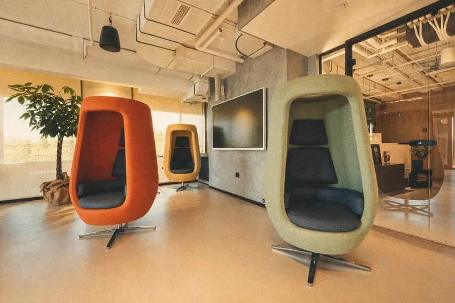 Three high-back acoustic egg chairs in orange, yellow, and green at Coinis HQ