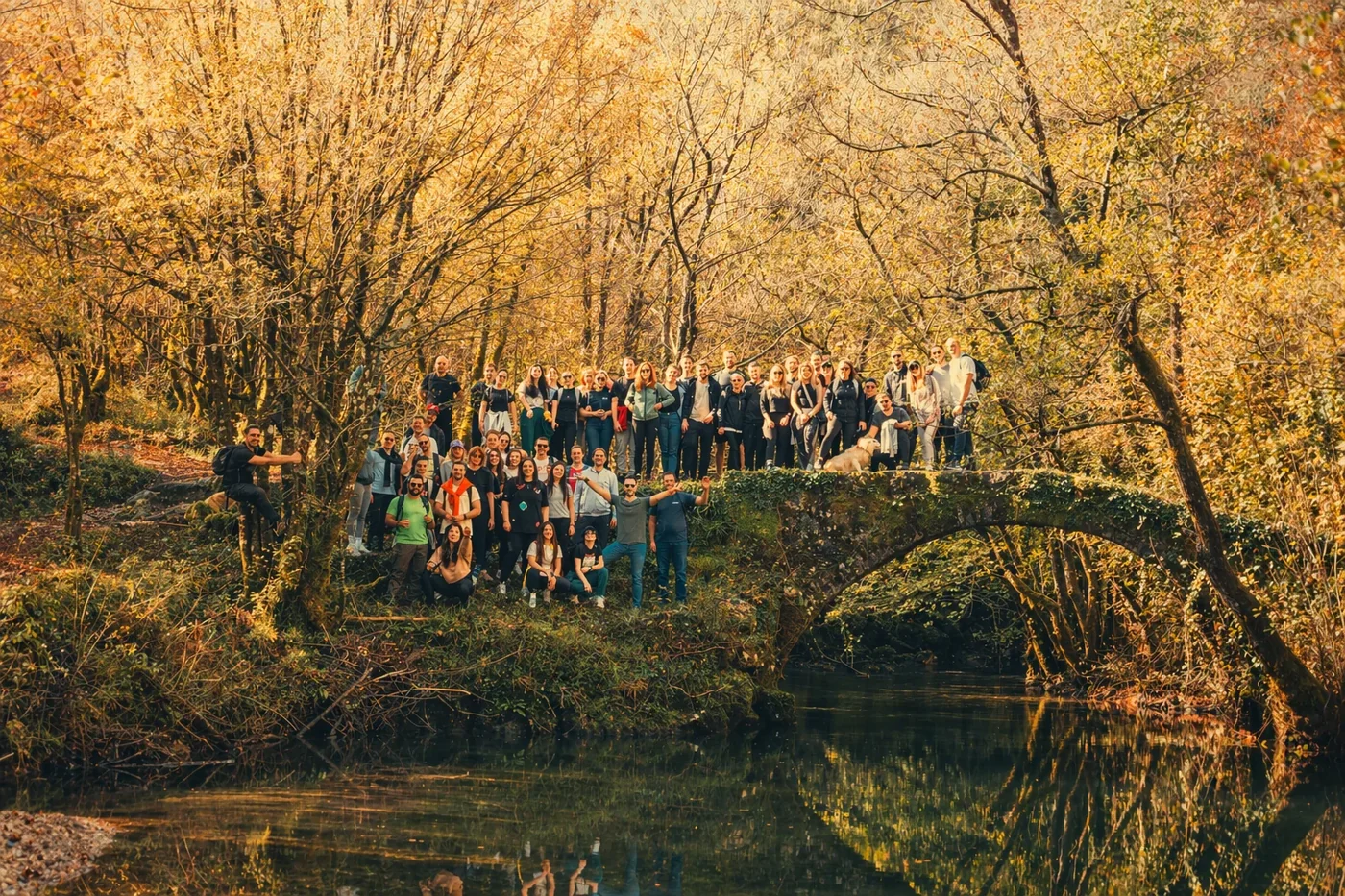 Coinis team posing for a large group photo on a bridge in nature